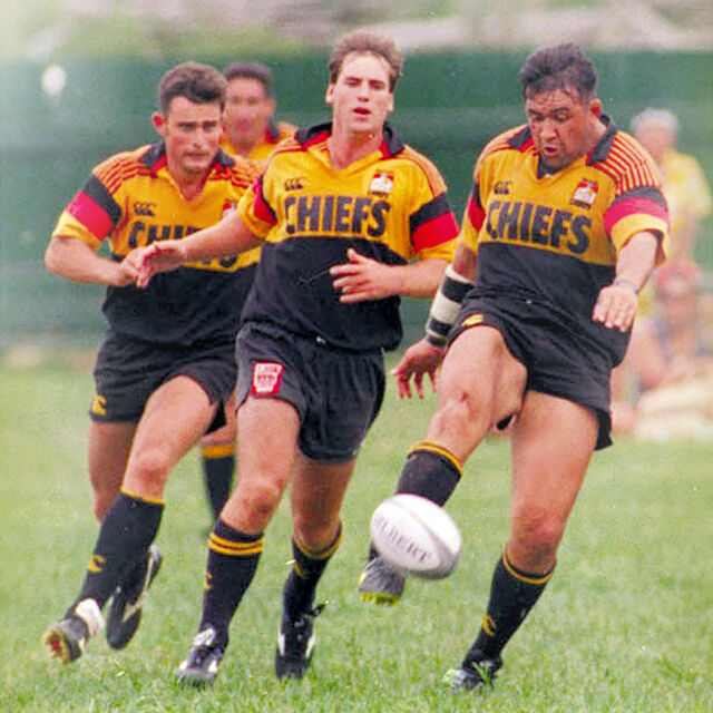 Chiefs player kicks downfield with teammates in support during an early Chiefs match.