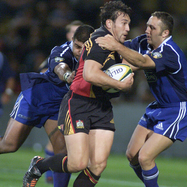 Chiefs player drives through tackles while holding possession under pressure.