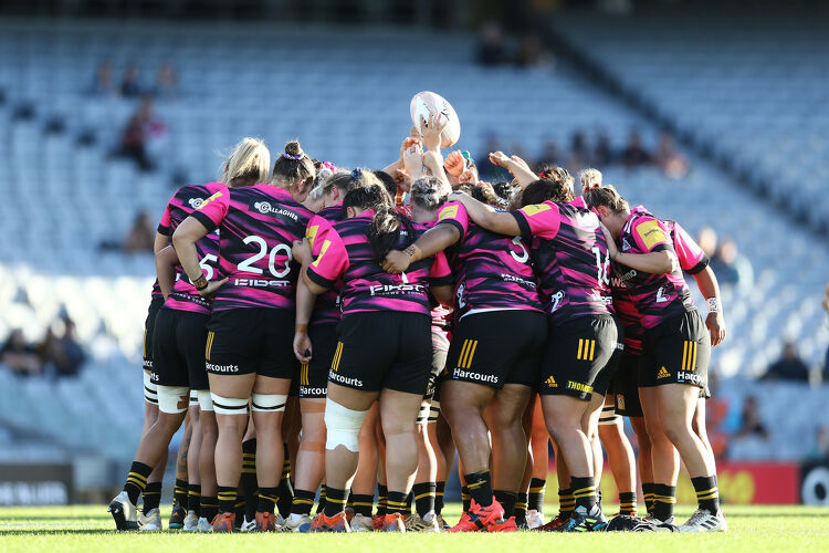 Chiefs Manawa players huddle together on the field, lifting the ball in unity before kick-off.