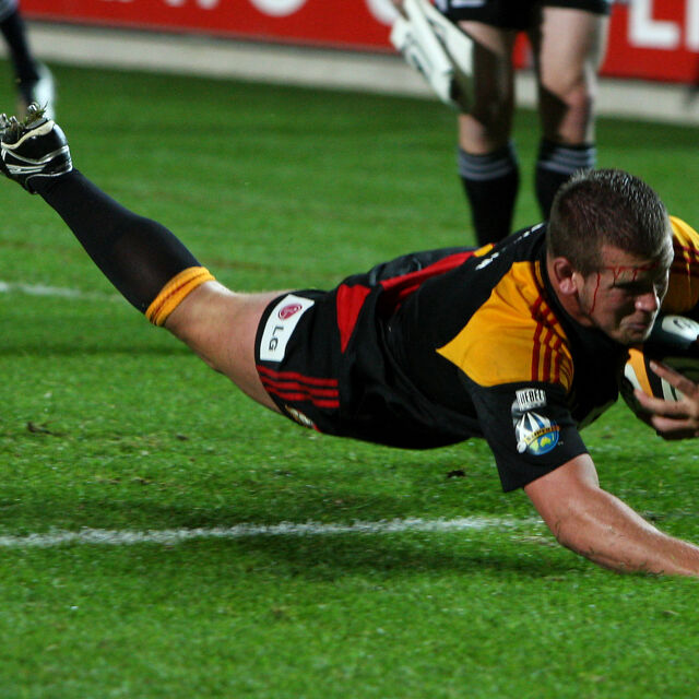 Chiefs player dives over the line to score a try, capturing speed and determination.