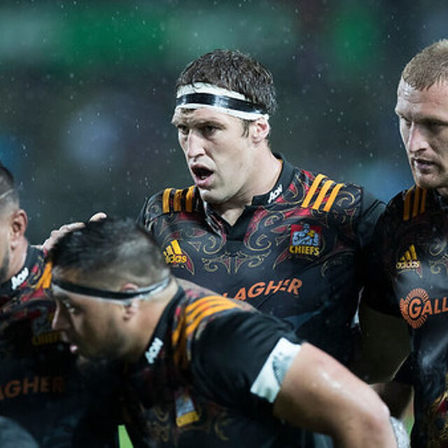 Chiefs players huddle during a Super Rugby match, showing focus and teamwork in tough conditions.